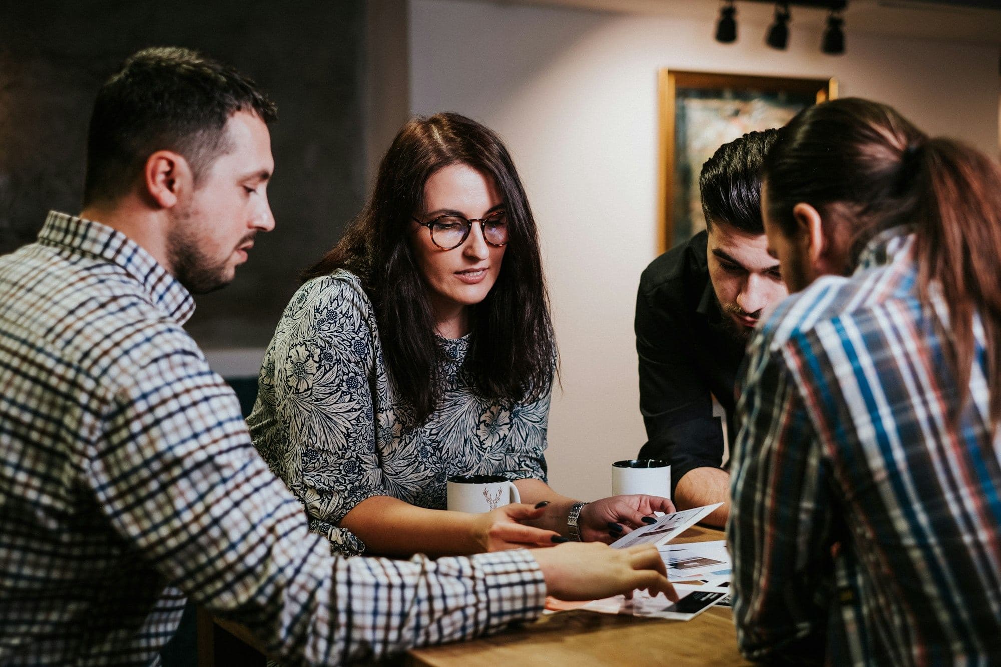 Four people reviewing documents together at a wooden table